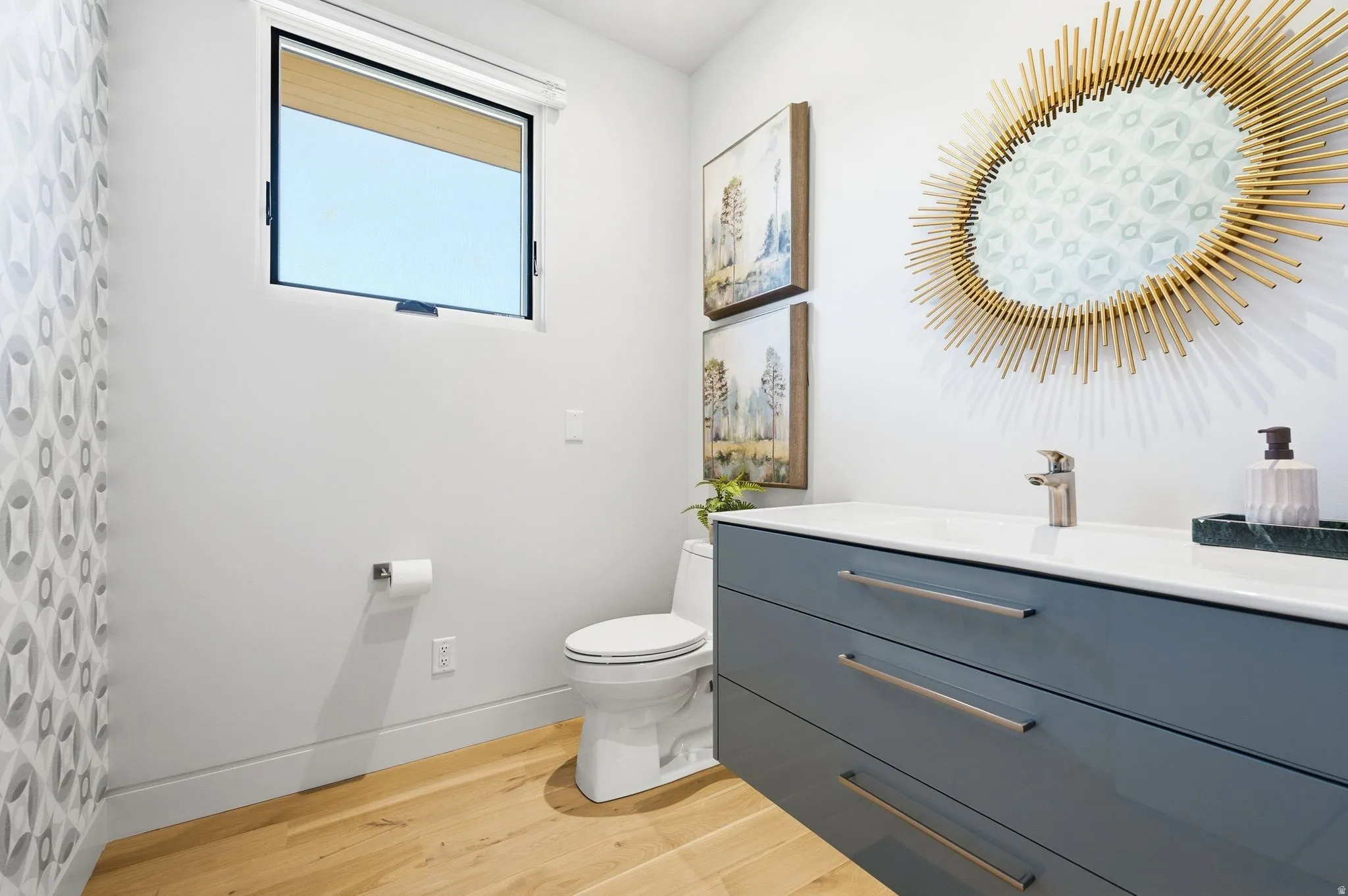 Floating vanity with integrated sink, wood-finish flooring, and a modern window