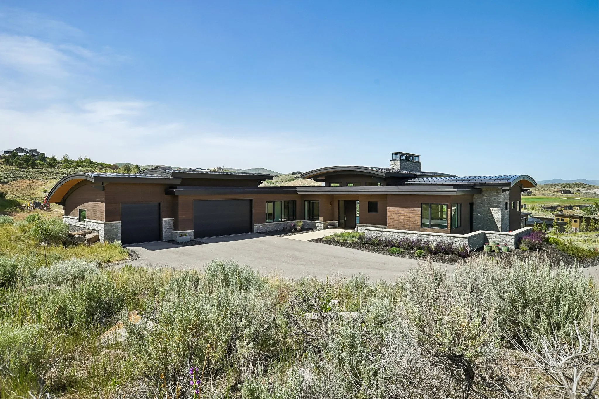Contemporary exterior featuring wood-look siding, stone accents, and curved rooflines