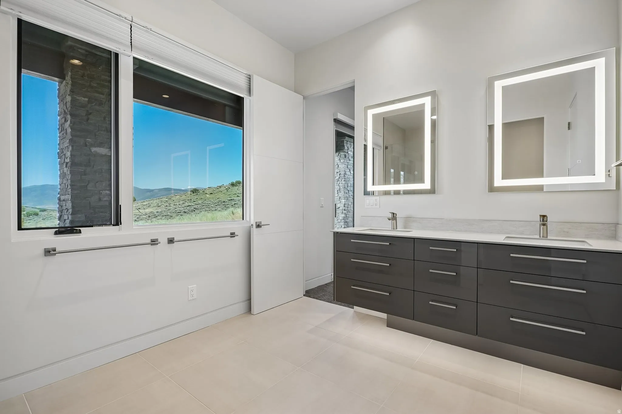 Contemporary bathroom featuring a floating dual vanity with undermount sinks, illuminated mirrors, and expansive windows