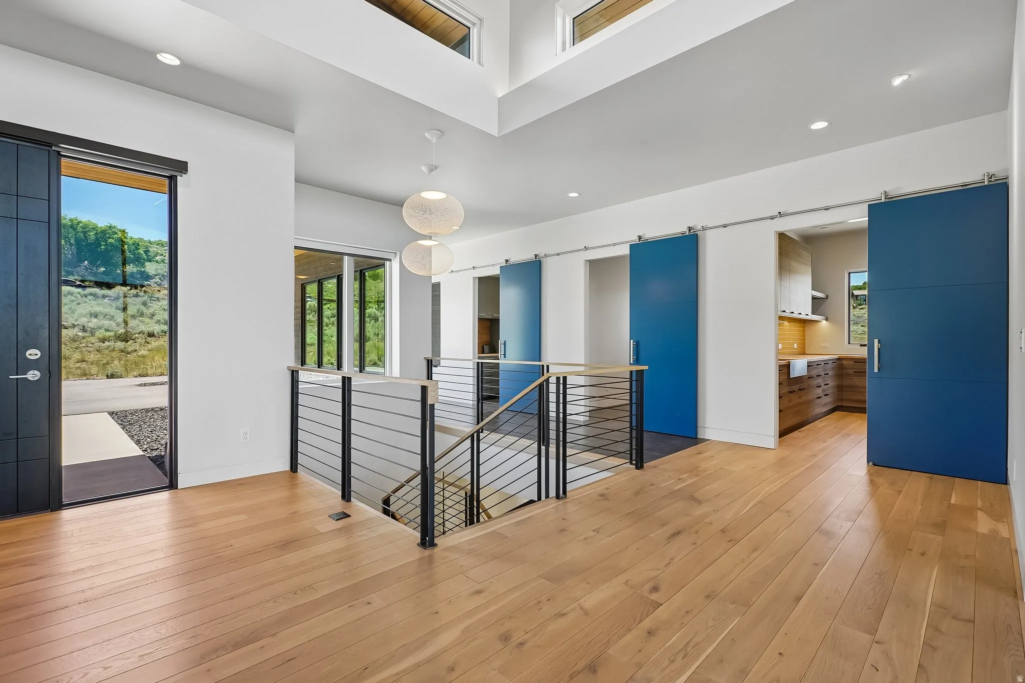 Upper-level landing featuring light wood-finish flooring, a modern cable railing staircase, and recessed lighting
