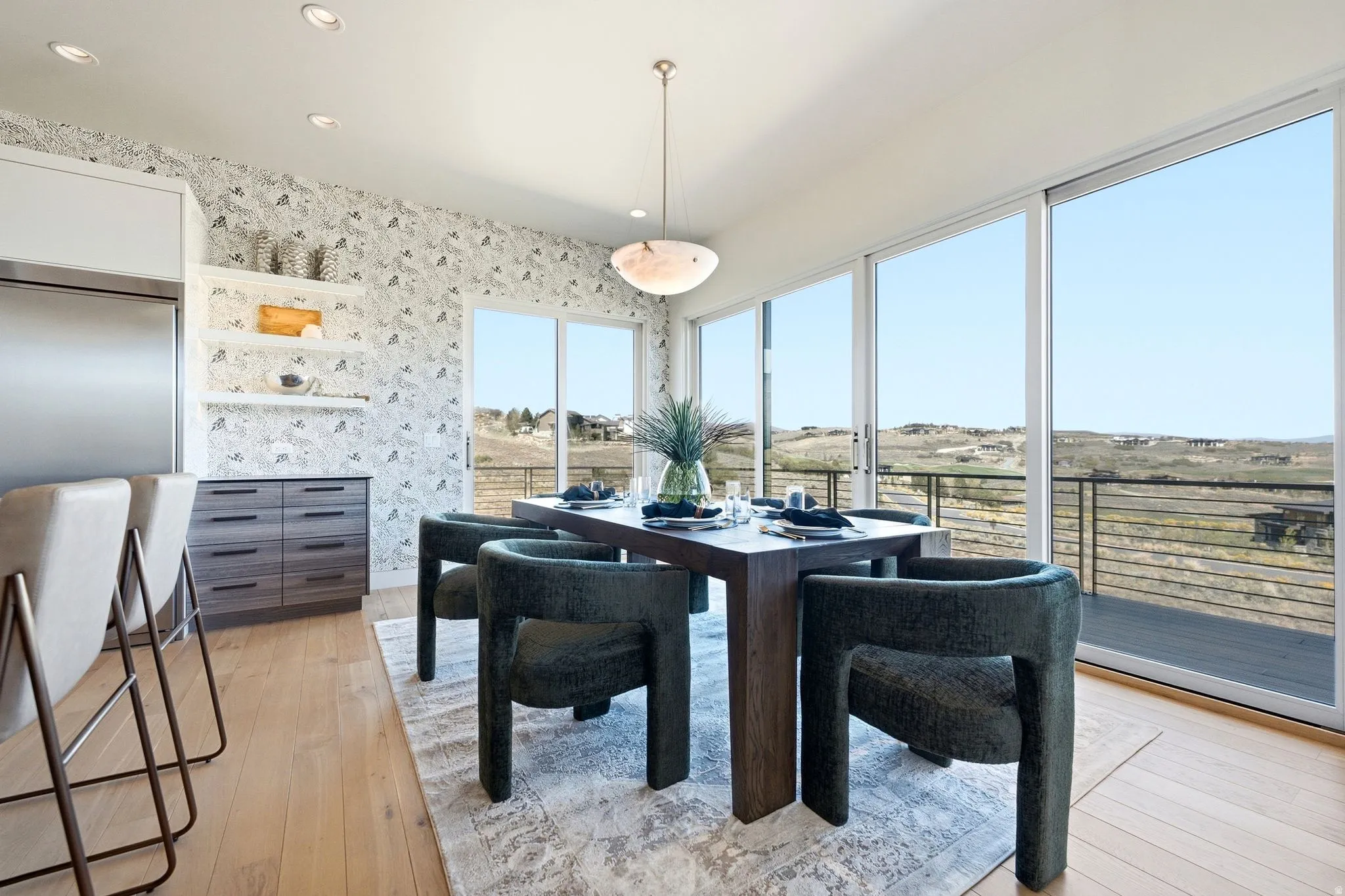 Expansive glass sliding doors, wood-finish flooring, recessed lighting, built-in shelving, and a contemporary pendant light fixture