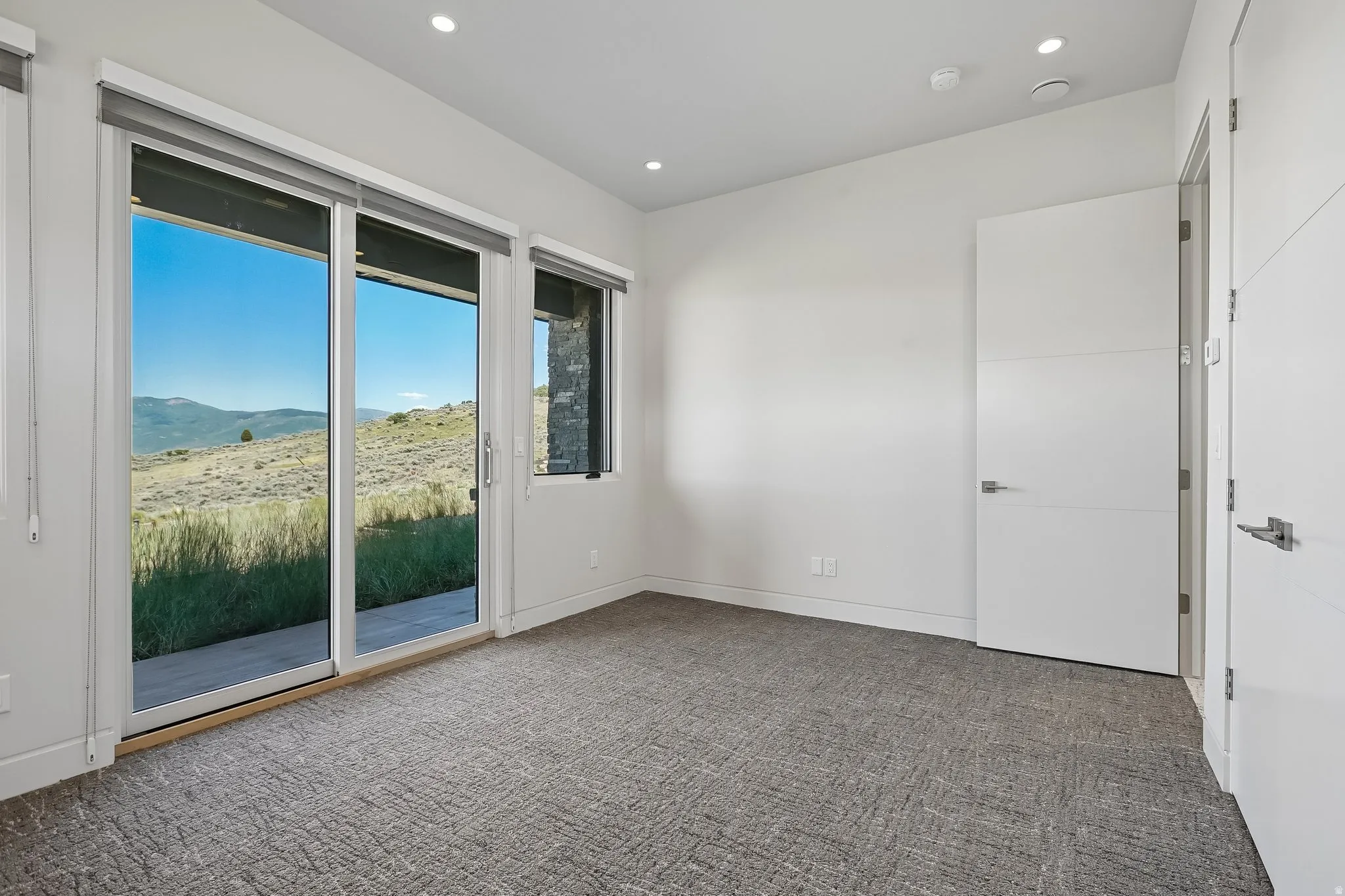Room featuring a sliding glass door to an outdoor area, a secondary window, and recessed ceiling lighting