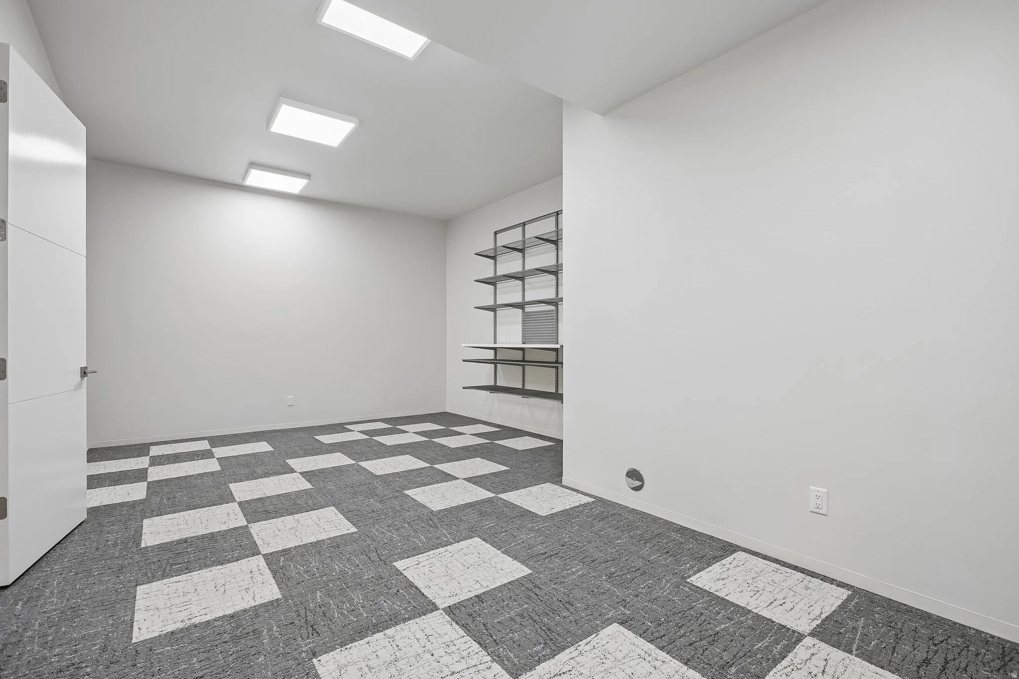 Spacious room featuring patterned carpet flooring, extensive built-in shelving, and contemporary recessed lighting