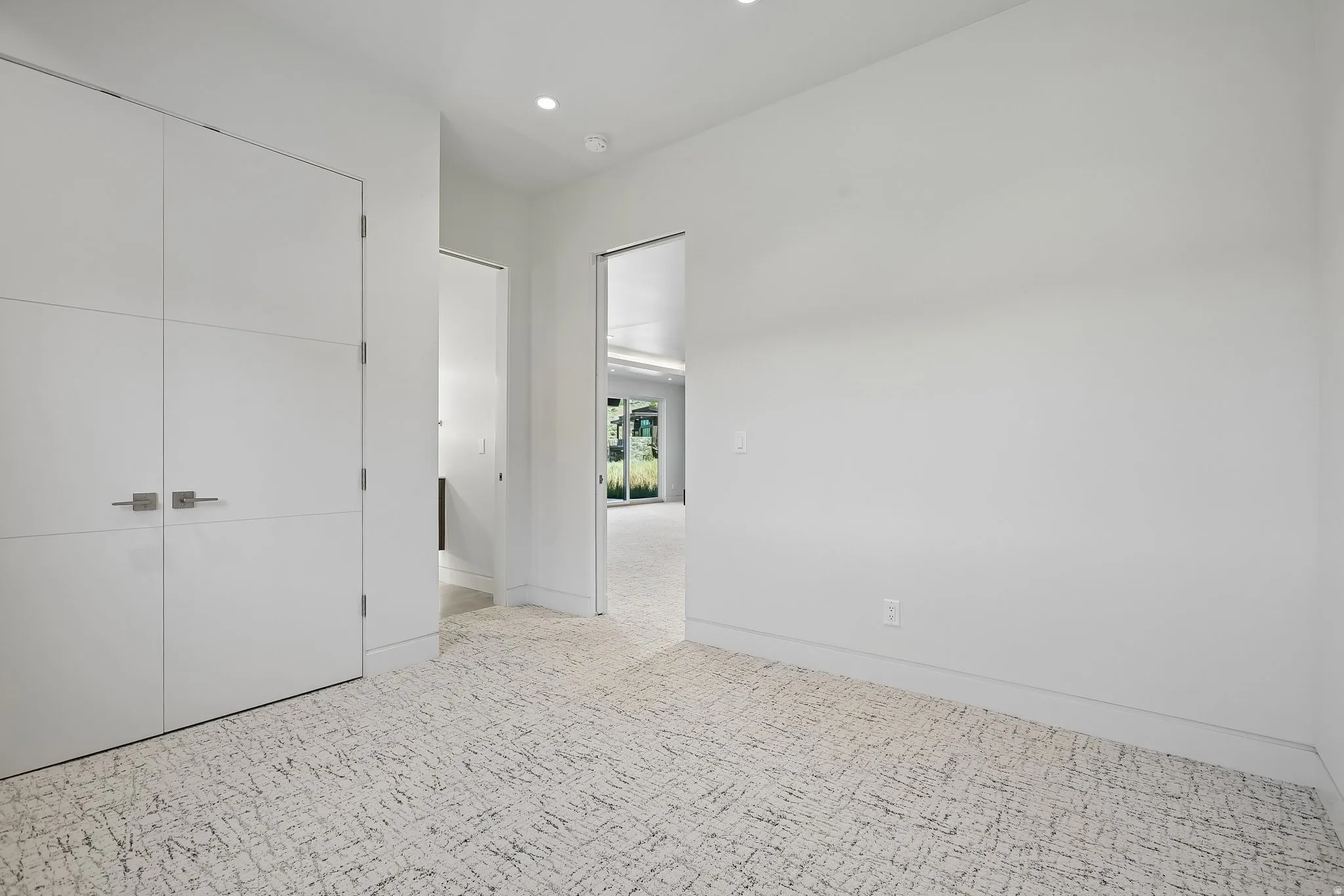 Neutral palette interior with textured carpet flooring, recessed lighting, and crisp white walls