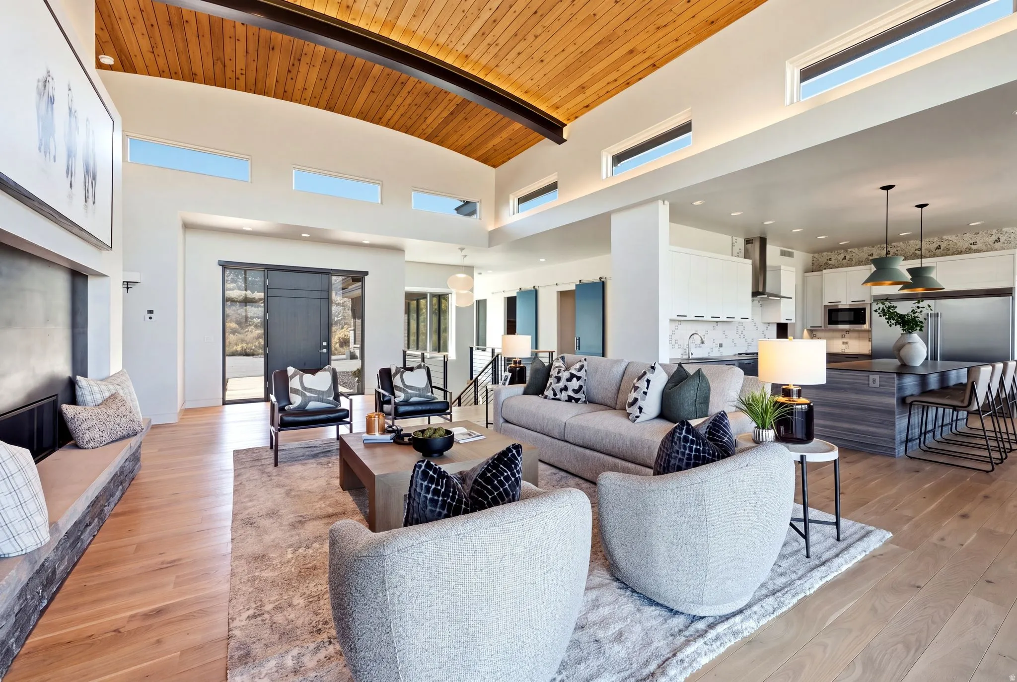 Vaulted wood-paneled ceiling, transom windows, wood-finish flooring, built-in bench seating, and a large kitchen island with pendant lighting