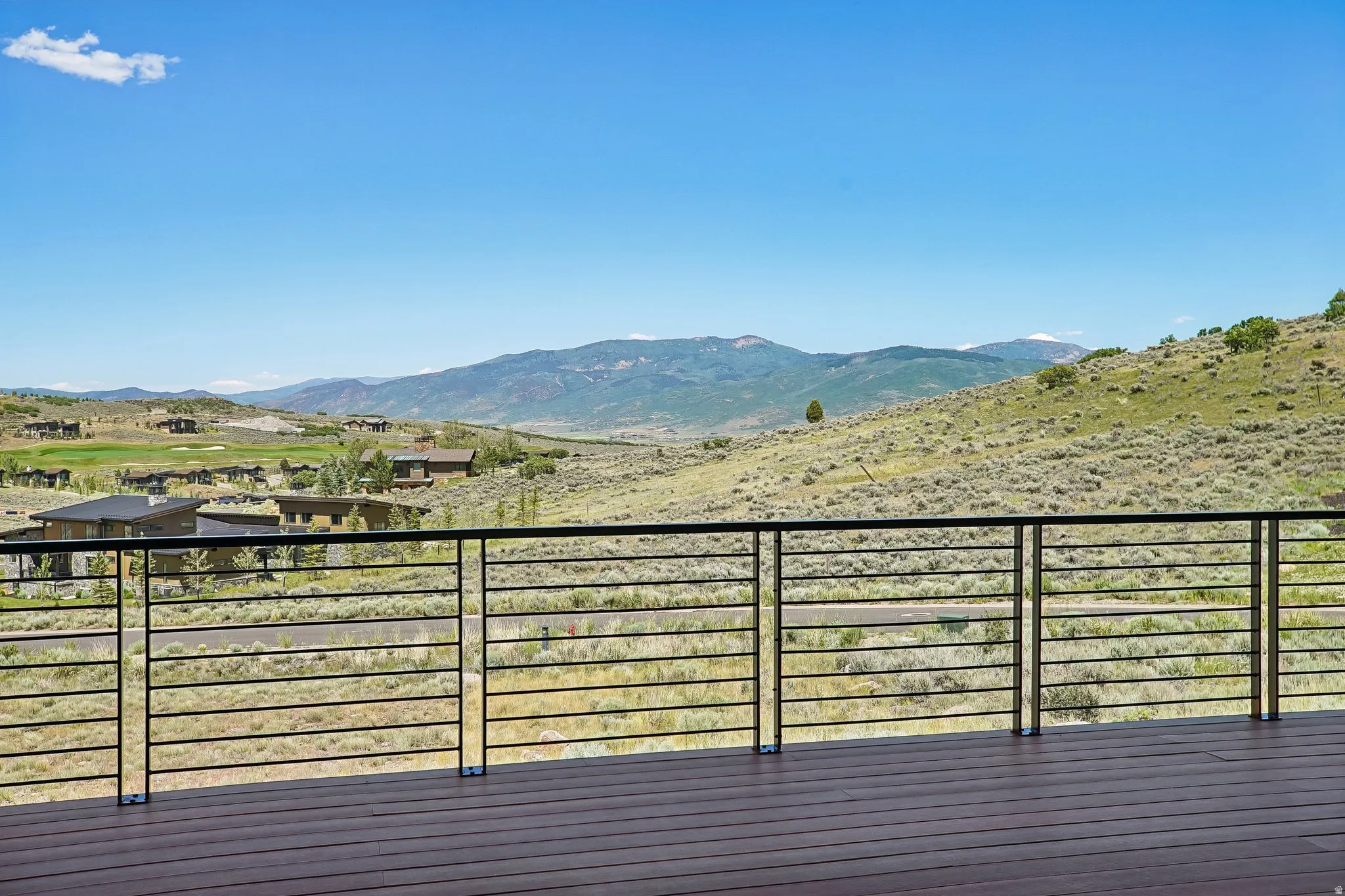 Expansive outdoor deck featuring wood-finish flooring and a contemporary horizontal bar railing