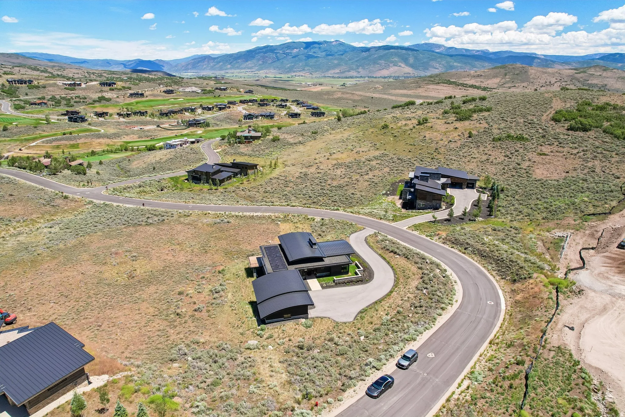 Modern residential property with a distinctive curved roofline, situated on a gently sloping lot