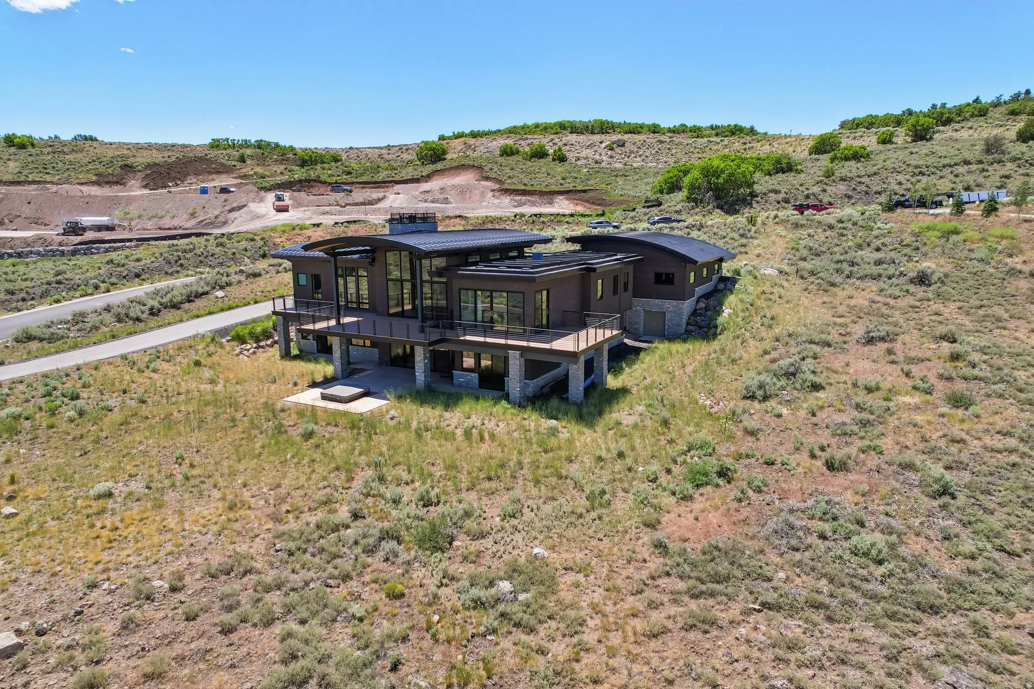 Modern architecture featuring extensive glazing, multiple outdoor decks, a lower-level patio, and a stone facade