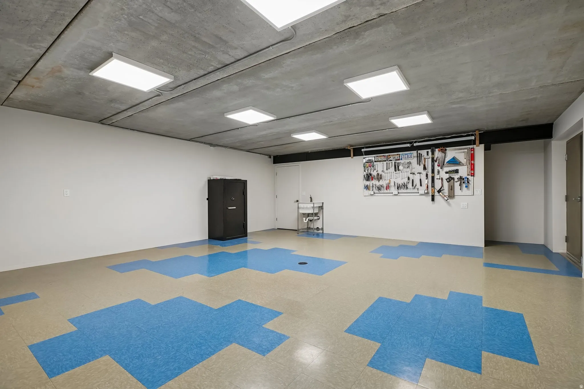 Spacious utility room featuring a concrete ceiling with recessed lighting, light-colored walls, and durable blue and beige patterned flooring