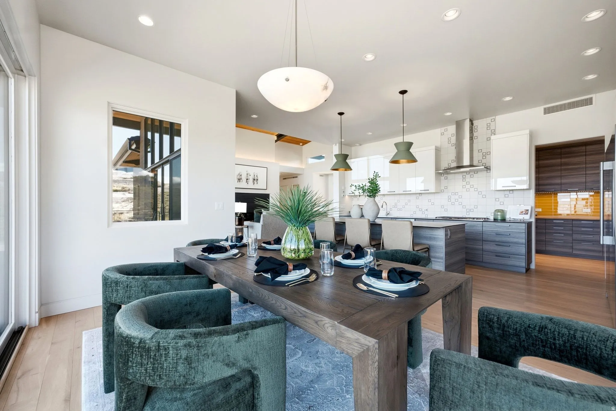 Open-concept dining area with wood-finish flooring, recessed lighting, and a modern chandelier