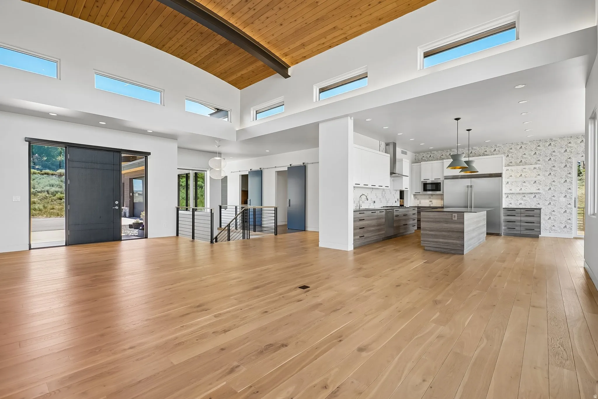 Vaulted wood-finish ceiling with exposed beam, complemented by light wood-finish flooring