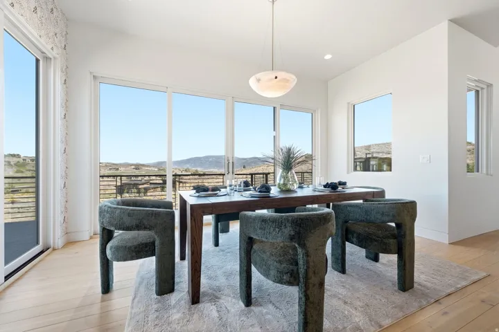 Expansive sliding glass doors, multiple large windows, recessed ceiling lighting, and a modern pendant light fixture