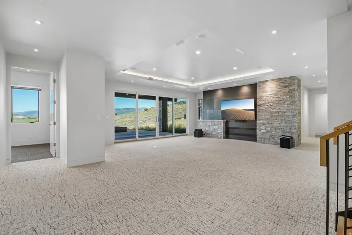 Spacious entertainment area featuring a stone accent wall, recessed lighting, and large sliding glass doors