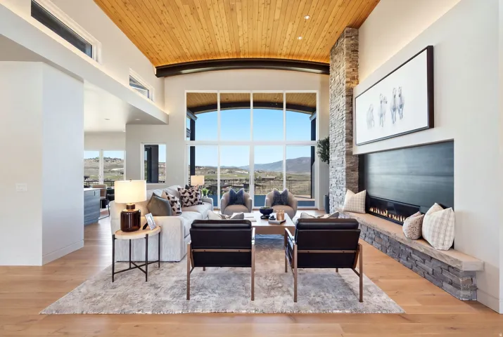 Vaulted wood-paneled ceiling, expansive two-story windows, stone-clad fireplace with hearth, recessed lighting, and wood-finish flooring
