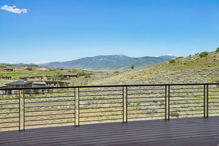 Expansive outdoor deck featuring wood-finish flooring and a contemporary horizontal bar railing