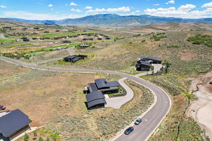 Modern residential property with a distinctive curved roofline, situated on a gently sloping lot