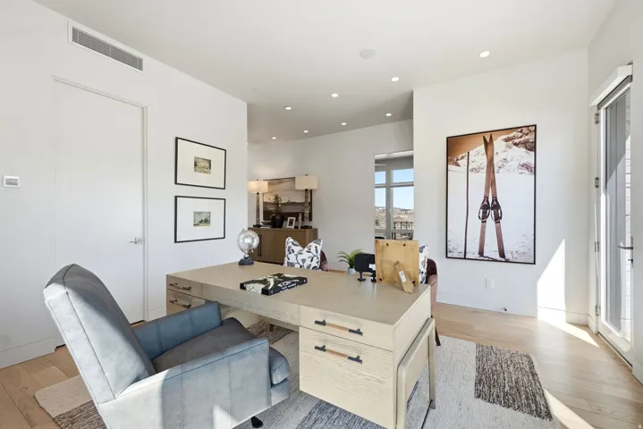 White walls with recessed lighting, wood-finish flooring, a full-light door, and a built-in linear vent