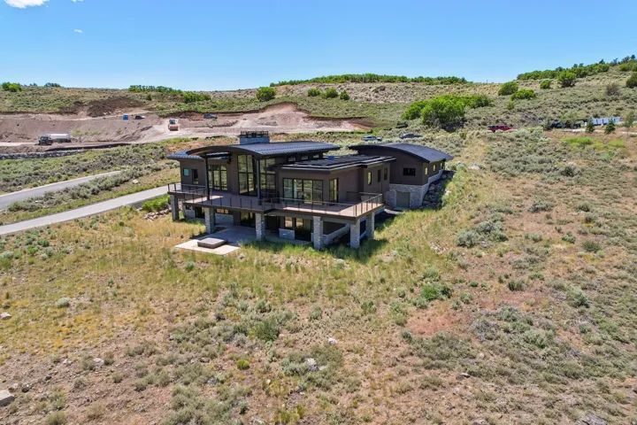Modern architecture featuring extensive glazing, multiple outdoor decks, a lower-level patio, and a stone facade