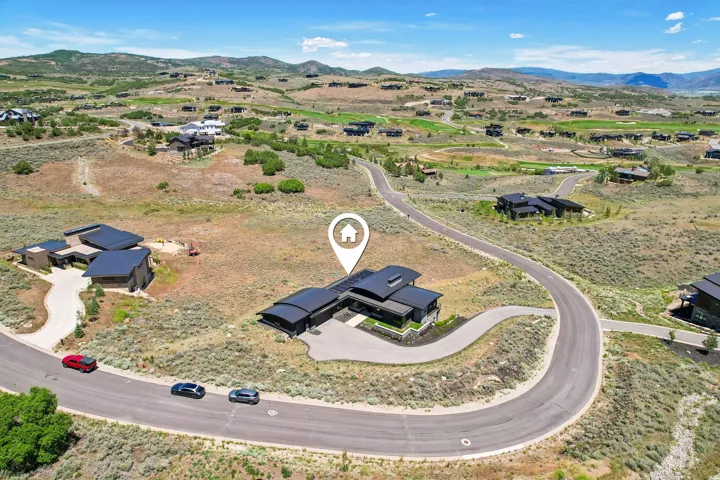 Modern architectural residence featuring a dark exterior, a curved driveway, and a flat roofline