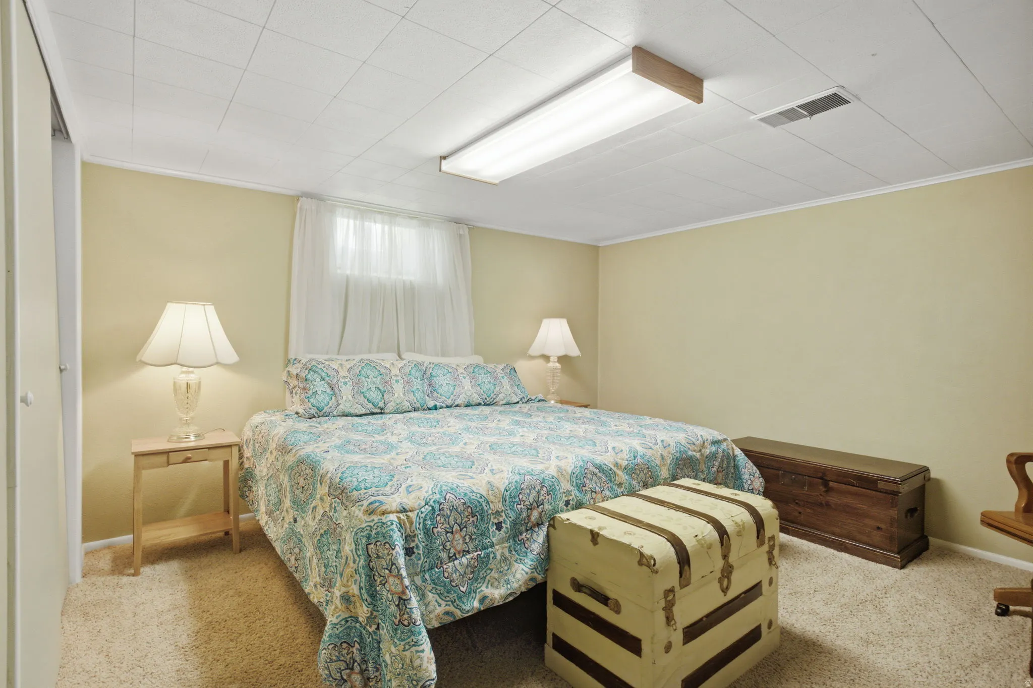 Carpeted bedroom featuring light-colored walls and a drop-tile ceiling