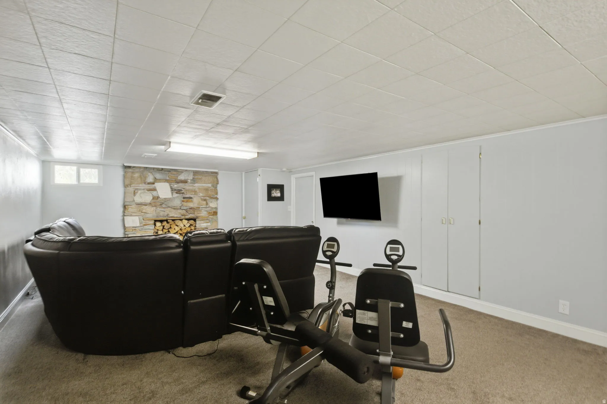 Recreational space featuring a stone fireplace, wall-mounted television, and built-in storage cabinetry