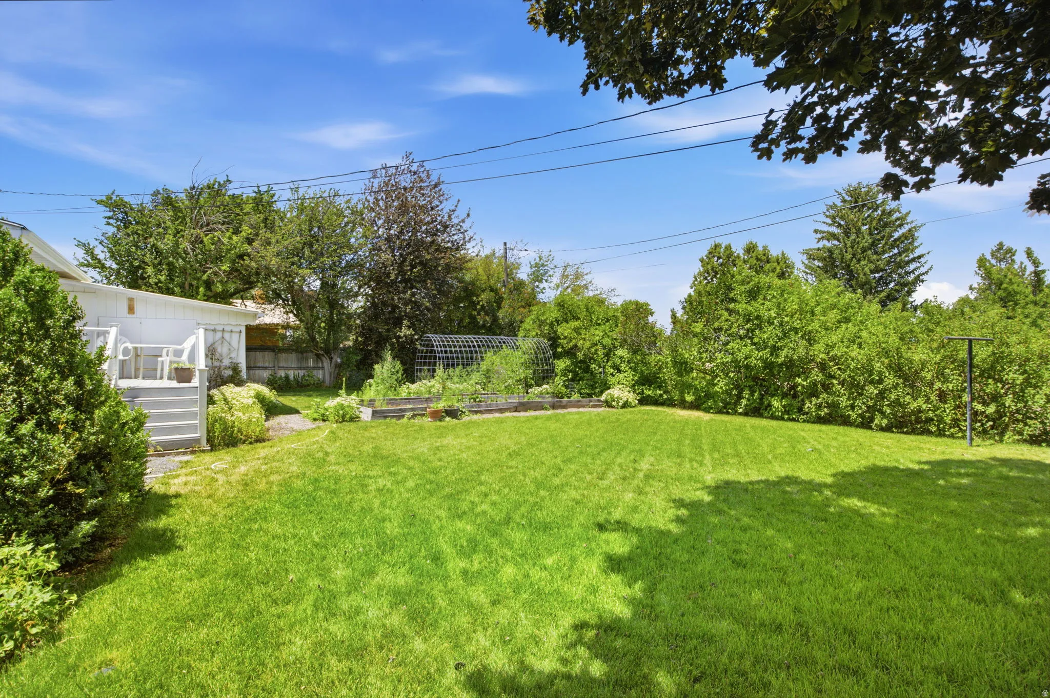 Expansive green lawn with a white exterior structure featuring a deck with stairs