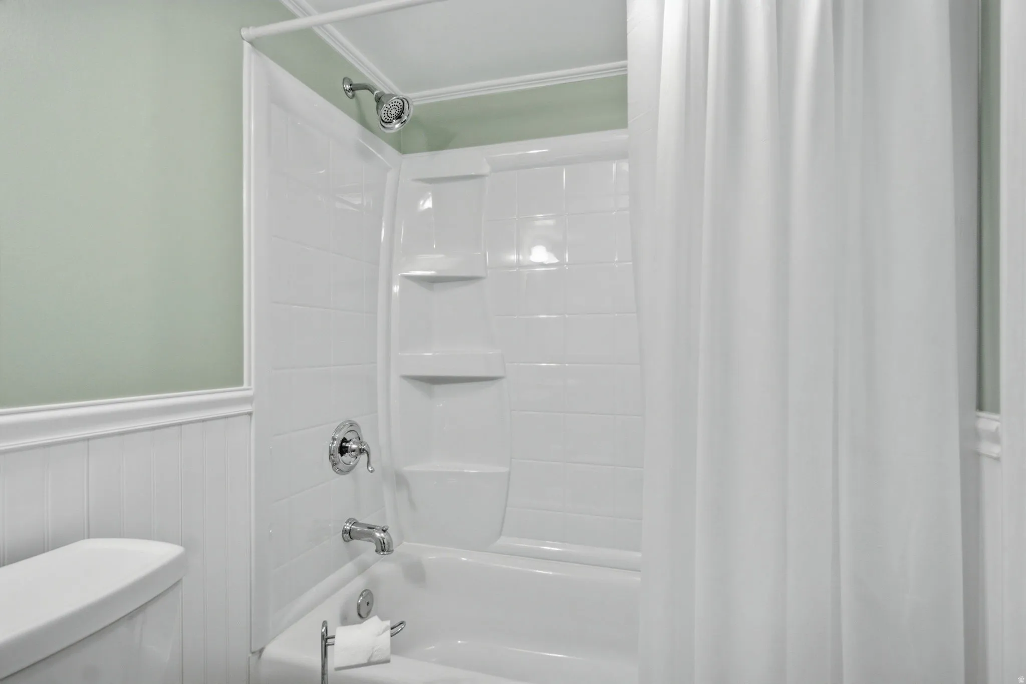 Bathtub and shower combination featuring a chrome shower head and faucet