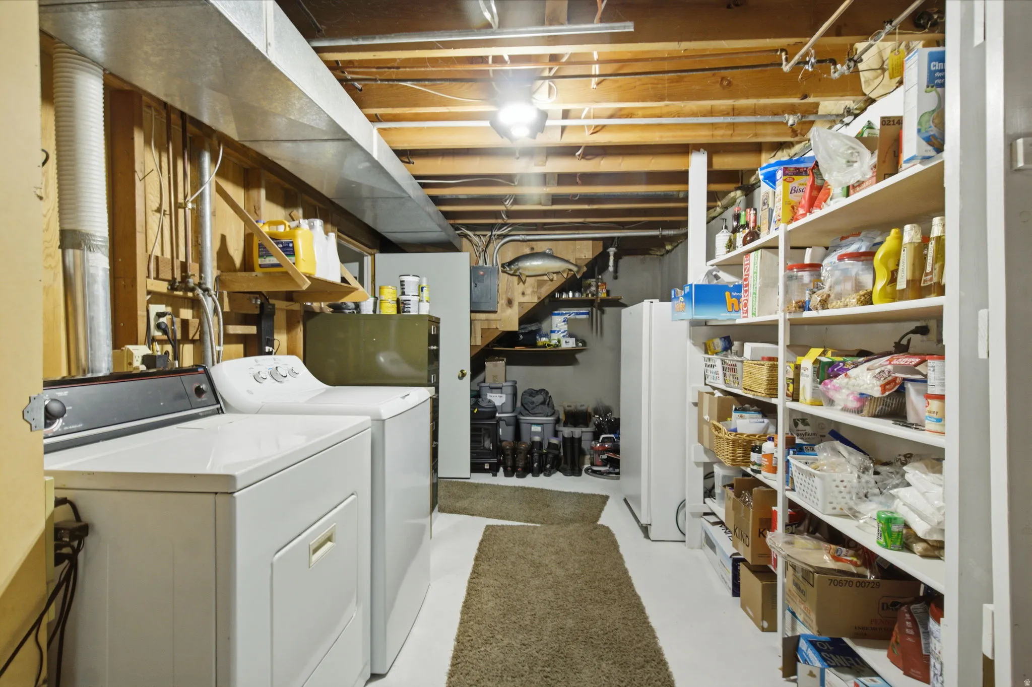 Utility area featuring laundry appliances, exposed wood beam ceiling, comprehensive shelving, and a small refrigerator