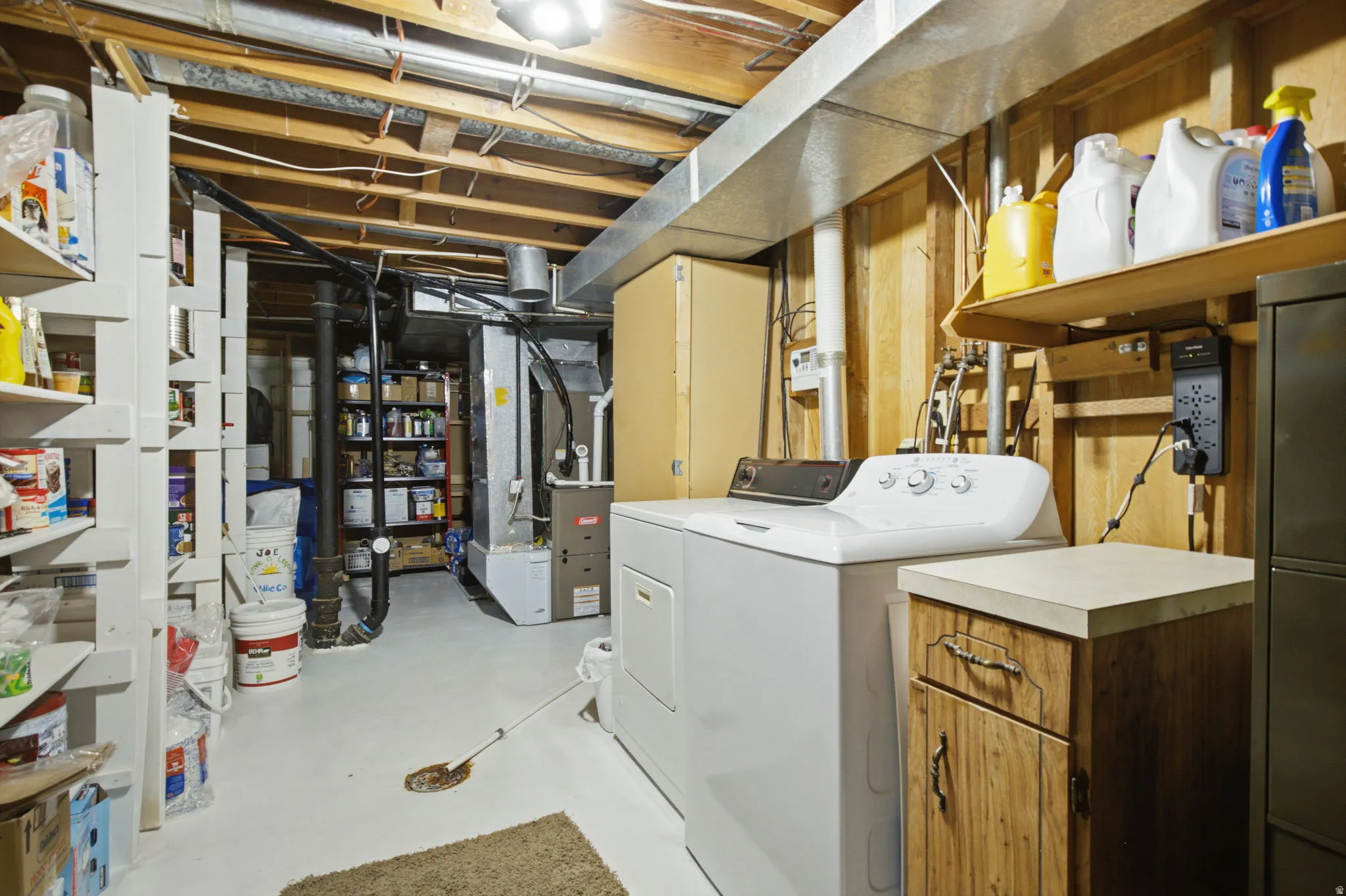 Utility area featuring a washer and dryer, exposed ceiling joists, and a painted concrete floor