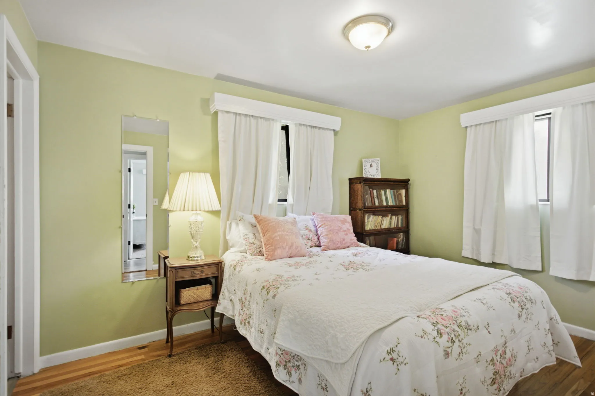 Bedroom with light green walls and wood-finish flooring
