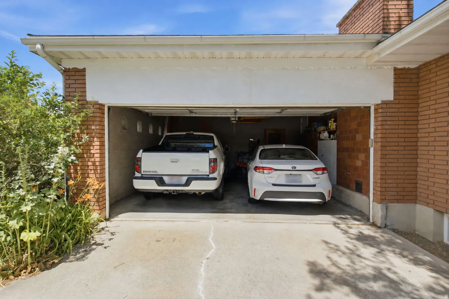 Two-car garage featuring a concrete drive, brick exterior, and white overhead door