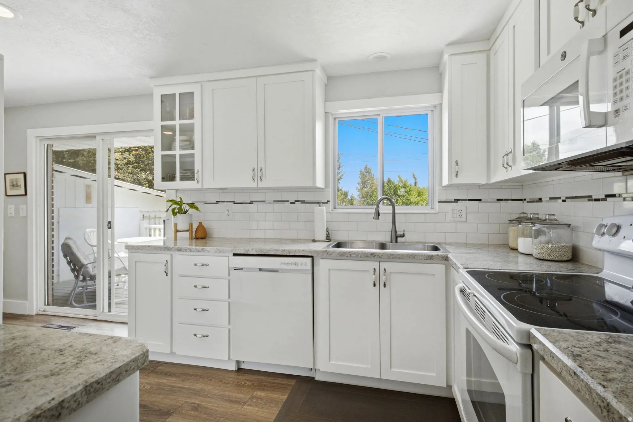 Bright kitchen featuring white cabinetry, stone-finish countertops, and stainless steel appliances