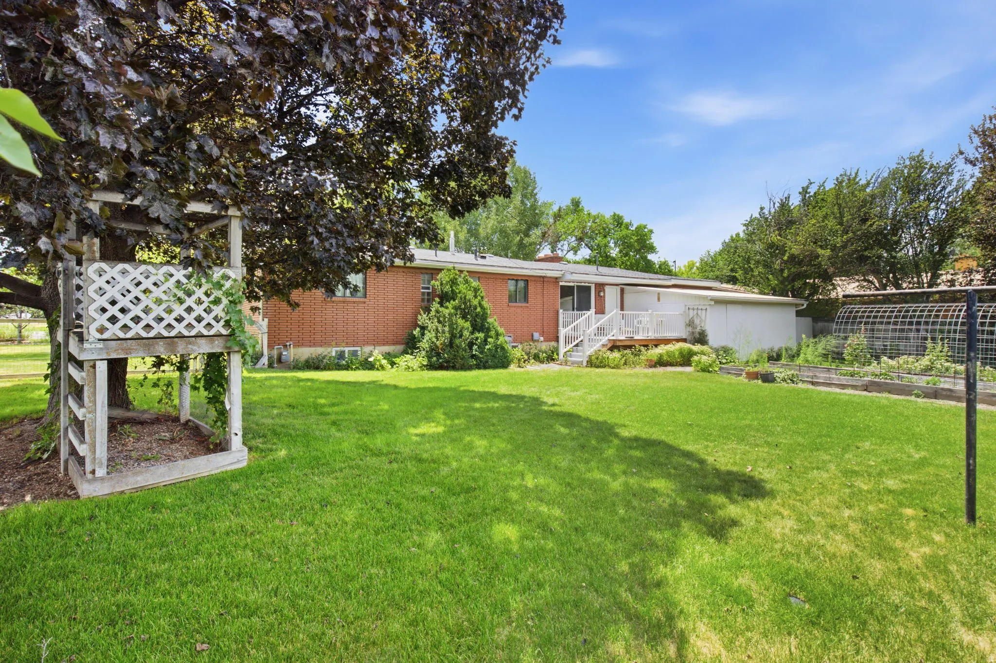 Expansive green lawn with mature trees and a built-in play structure