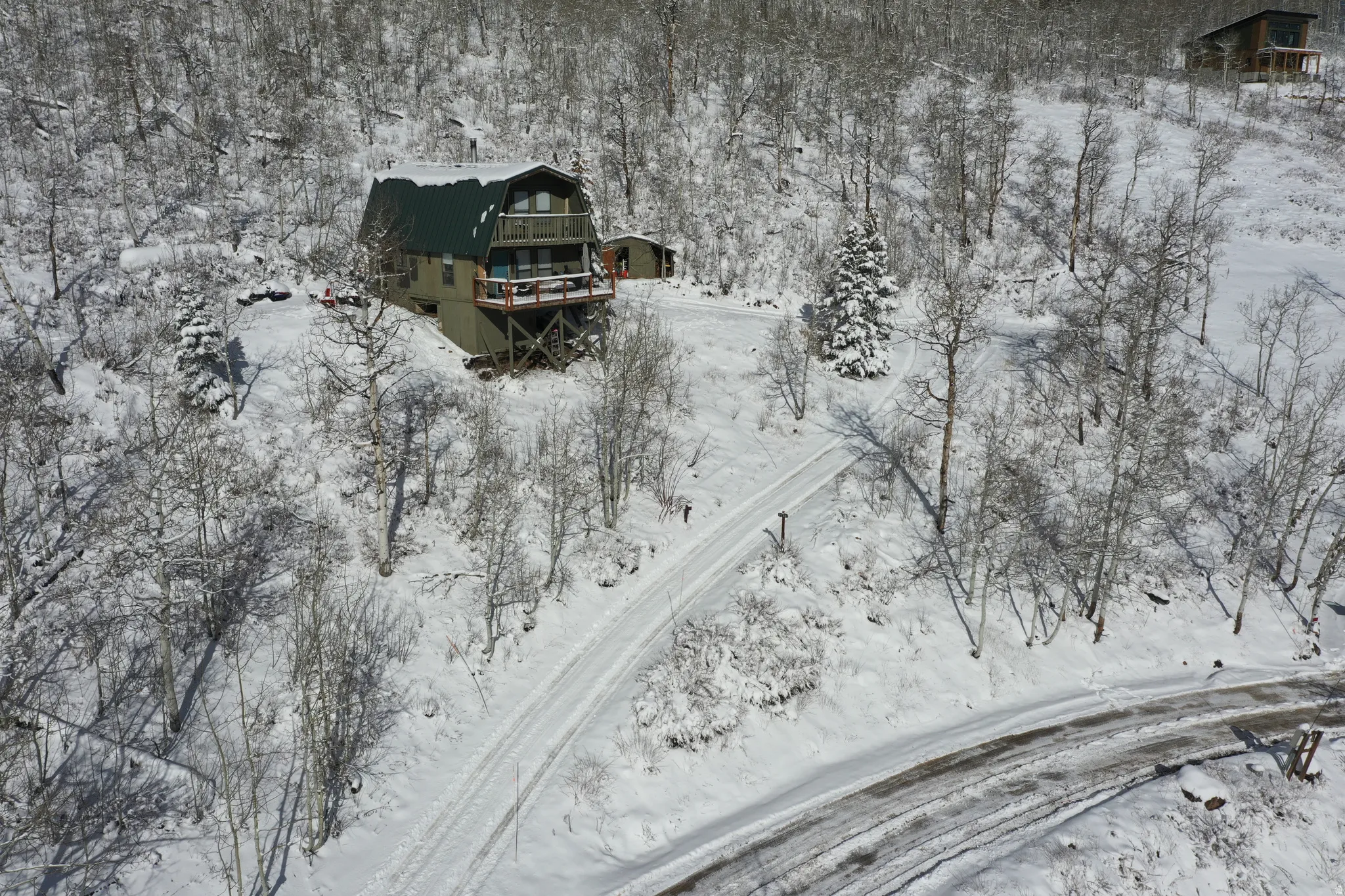 Elevated home with a green metal roof, multiple balconies, and a distinctive gambrel roofline