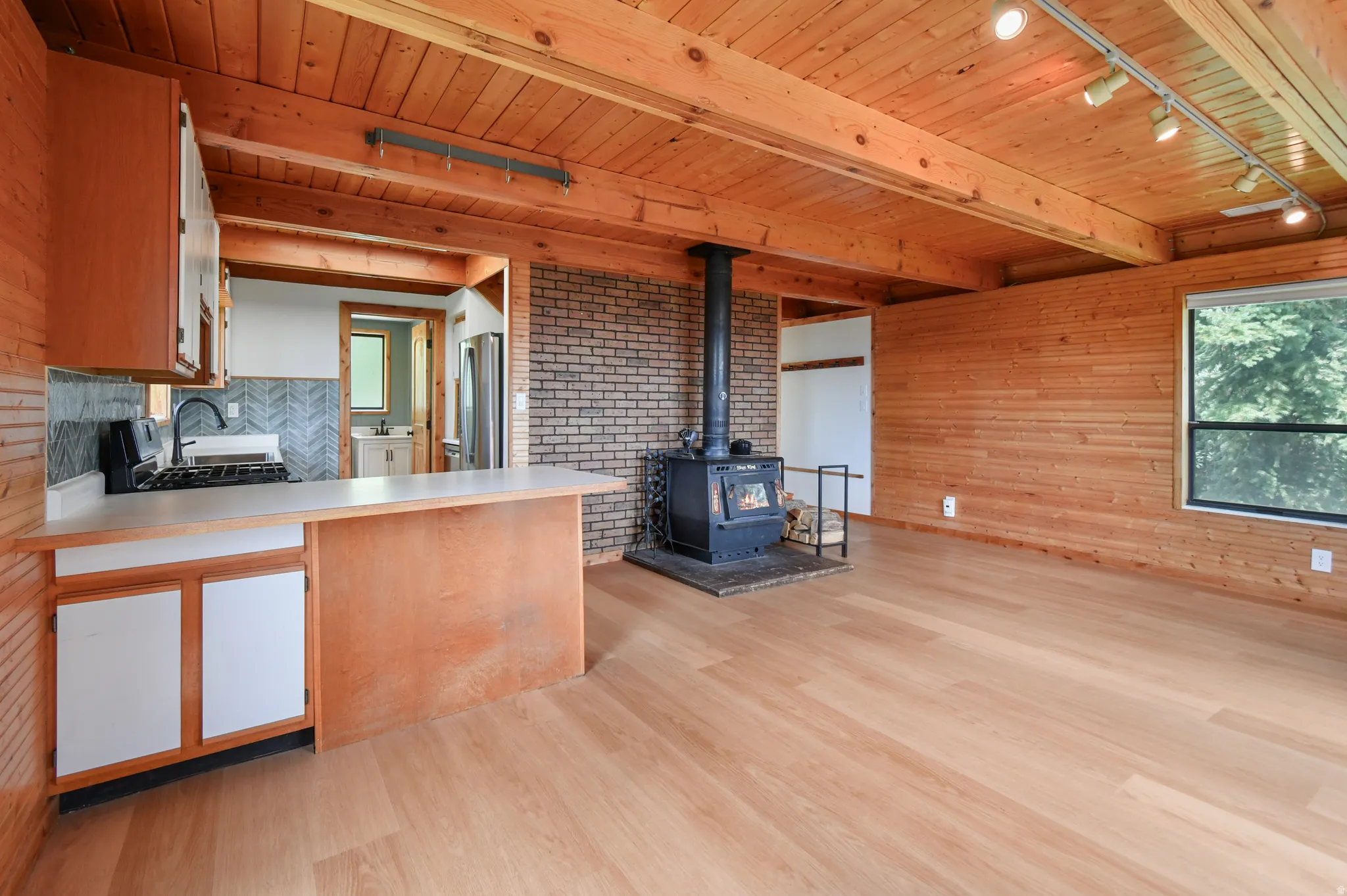 Wood-finish flooring throughout, complemented by a wood-paneled wall and exposed wood beam ceiling