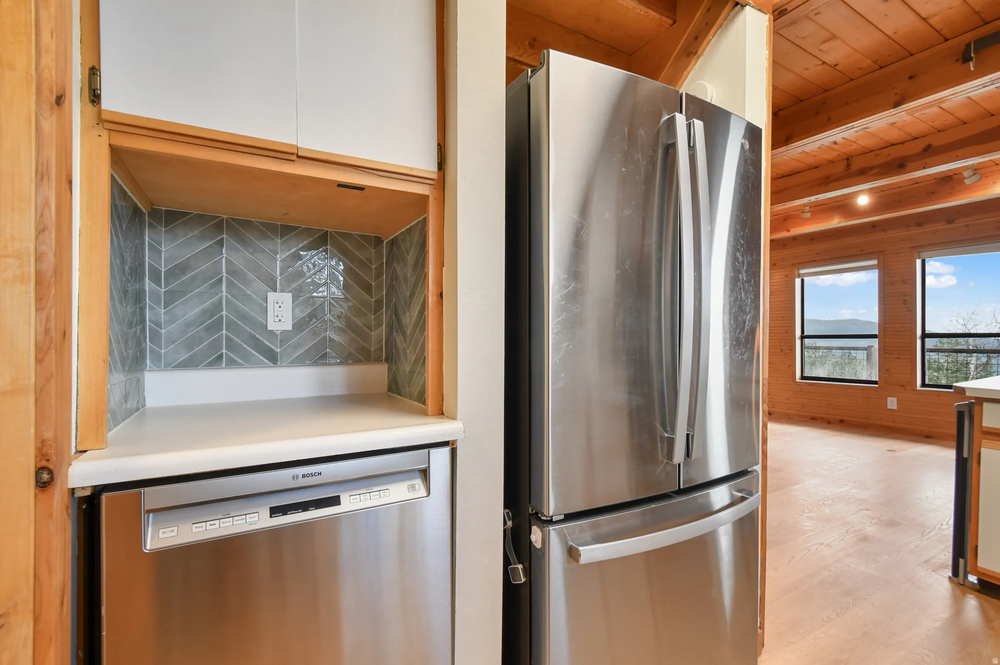 Kitchenette with a Bosch stainless steel dishwasher, a solid surface countertop, and a gray herringbone tile backsplash