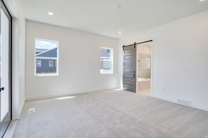 Spacious room featuring light-toned carpeting, recessed ceiling lighting, and multiple windows