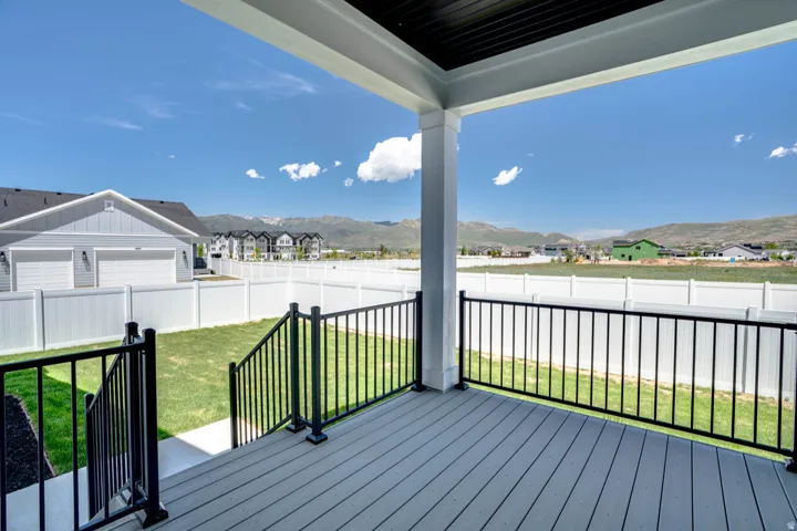 Covered deck featuring composite wood-finish flooring, black metal railings, and a white support column
