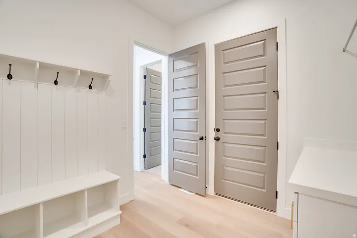 Entryway featuring light wood-finish flooring, white built-in shiplap bench with storage cubbies, and a coat rack with black hooks