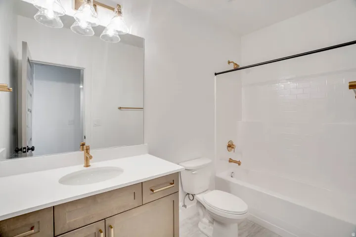 Bathroom featuring a wood-finish vanity with a light countertop, an oval undermount sink, and brass-tone hardware