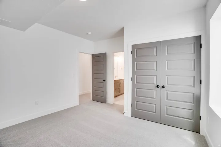Neutral-toned carpeting, white walls, and a white ceiling with recessed lighting