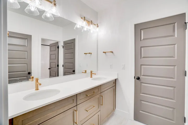 Double vanity with white countertops, undermount sinks, and gold-finish faucets