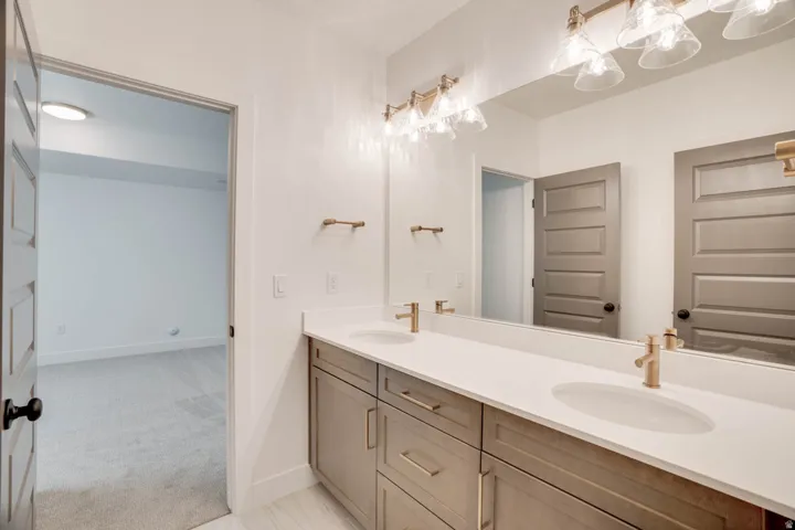 Dual vanity with light-colored countertops, undermount sinks, and gold-toned faucets