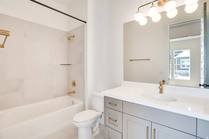 Bathroom featuring a vanity with a white countertop and gray cabinetry, an undermount sink, and gold-finish fixtures