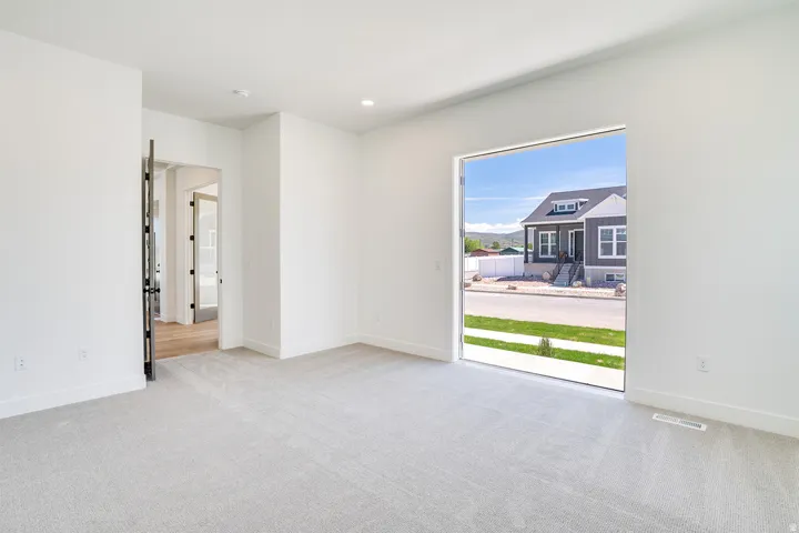 Spacious room featuring light-colored carpeting, recessed lighting, and a large picture window