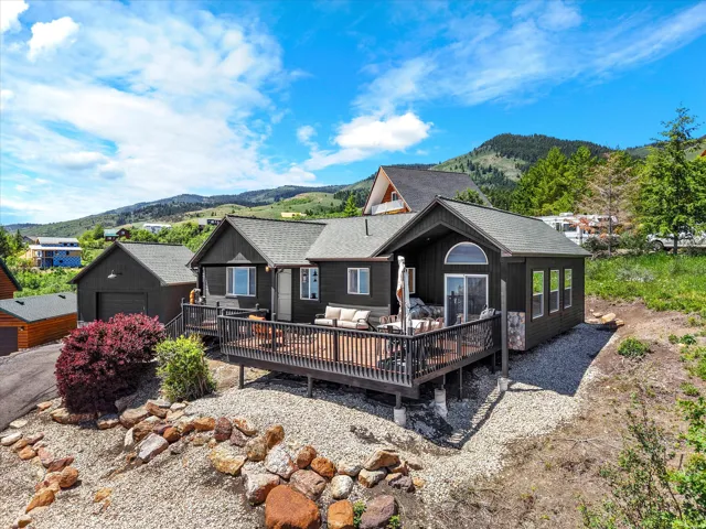 Exterior showcasing a spacious deck with dark railing, a detached garage, and a gravel landscape