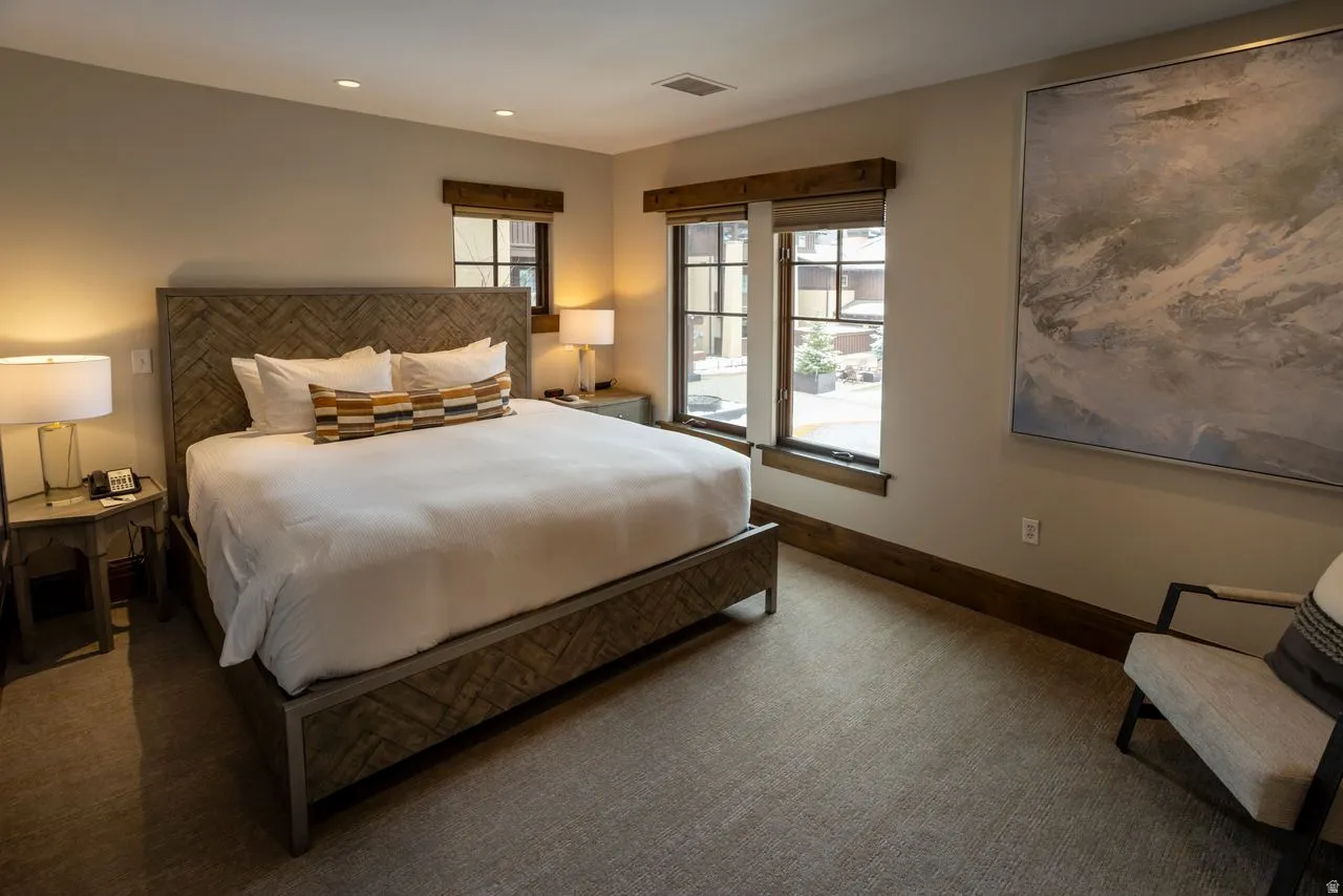 Spacious bedroom featuring a textured wood-finish bed frame, recessed lighting, and large windows with wood trim