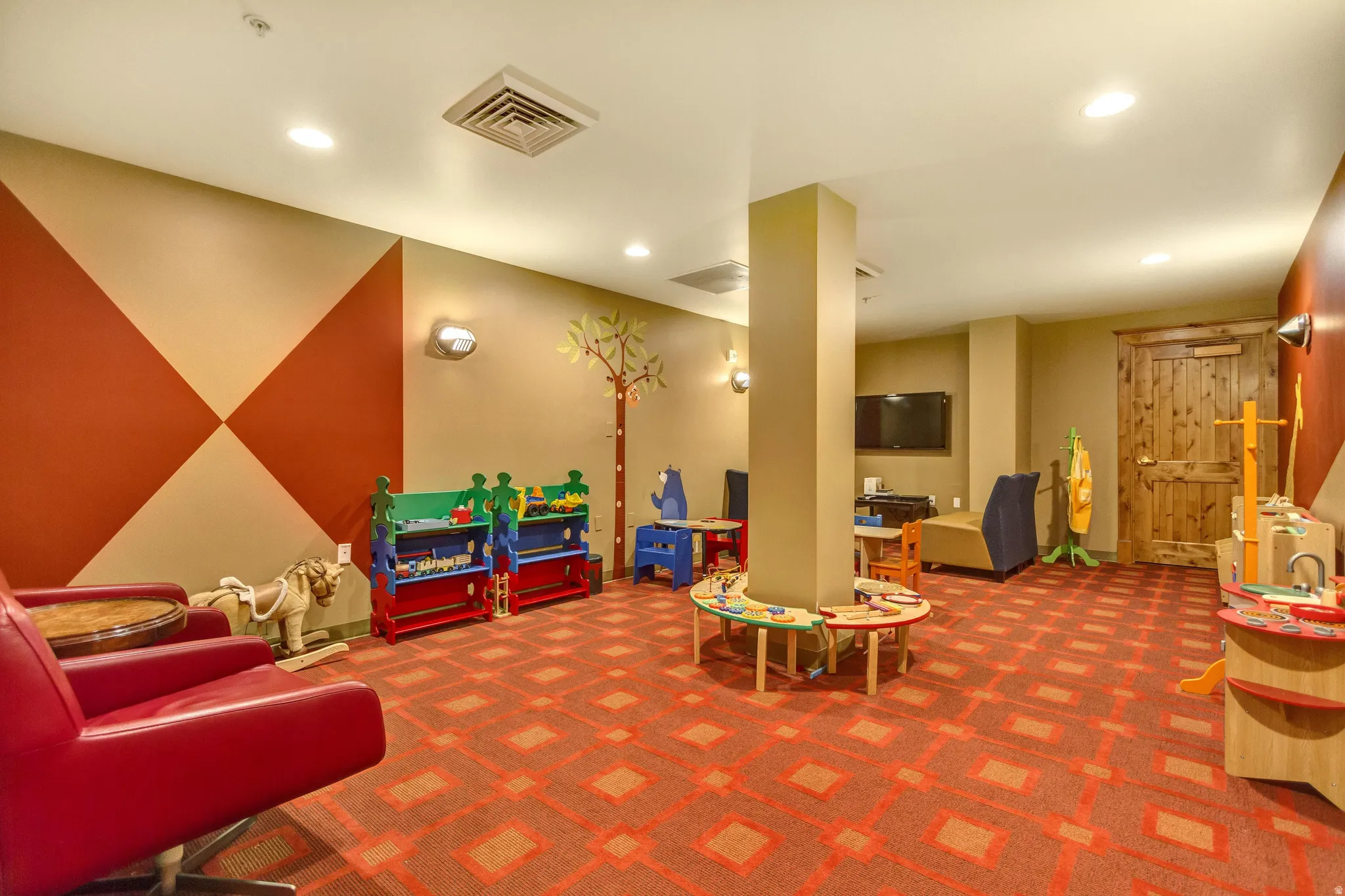 Spacious activity room featuring patterned carpeting, recessed lighting, and accent walls