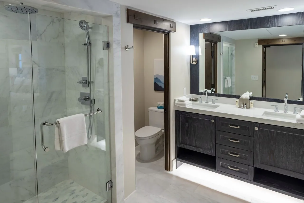 Spacious bathroom featuring a dual vanity with a light-toned countertop, dark wood-finish cabinetry, and a large framed mirror