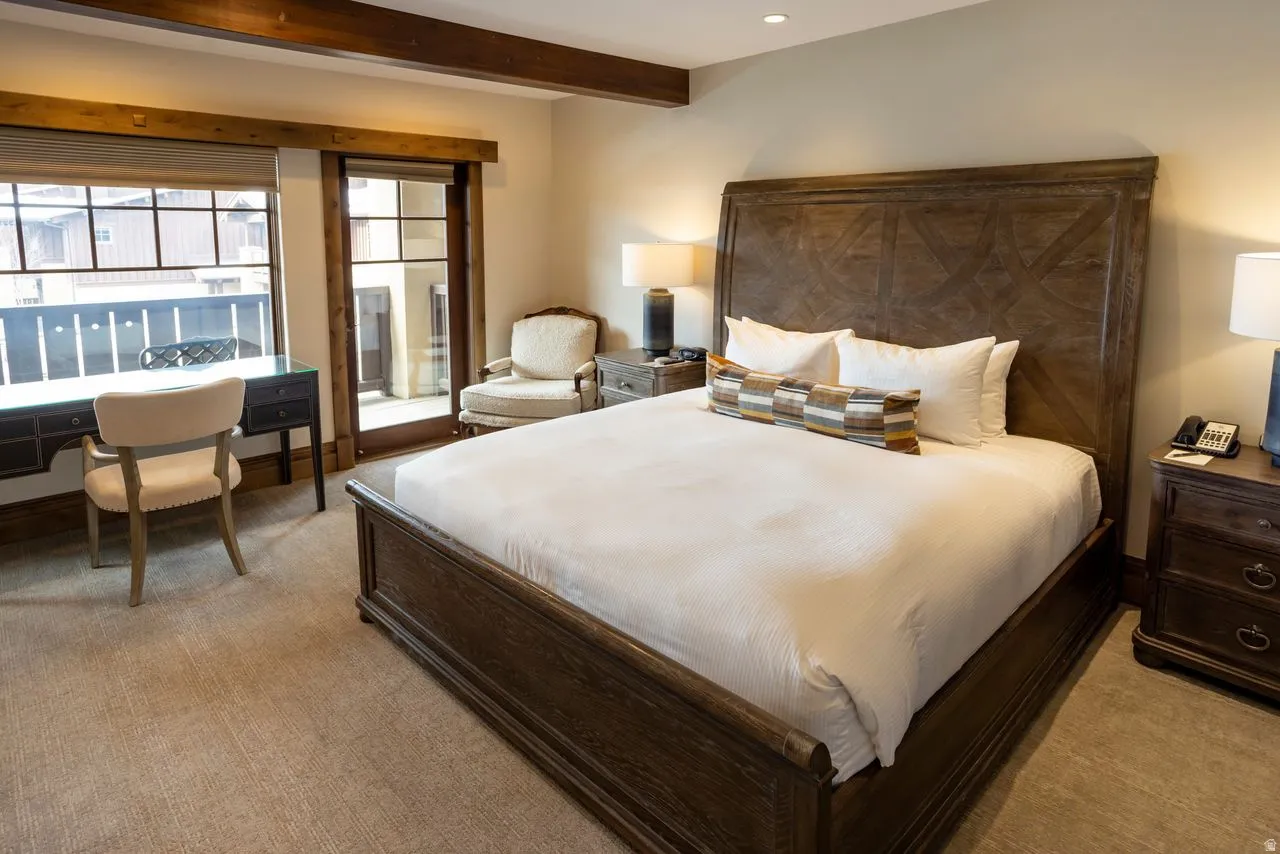 Spacious room with exposed wood beams, large window, and direct outdoor access